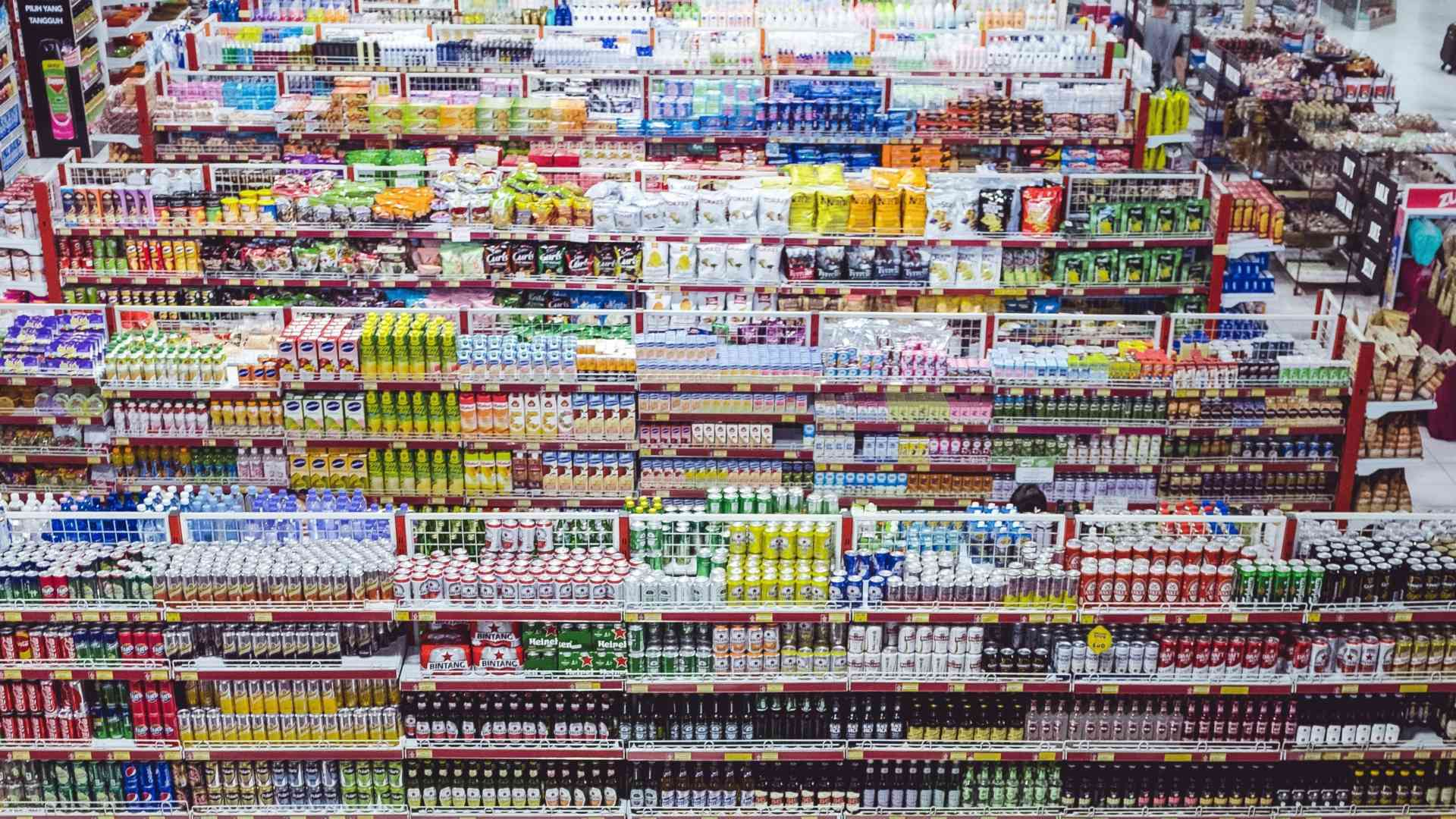 Vollständig bestückte Supermarktregale mit bunten Produktverpackungen in einem Einzelhandelsgeschäft